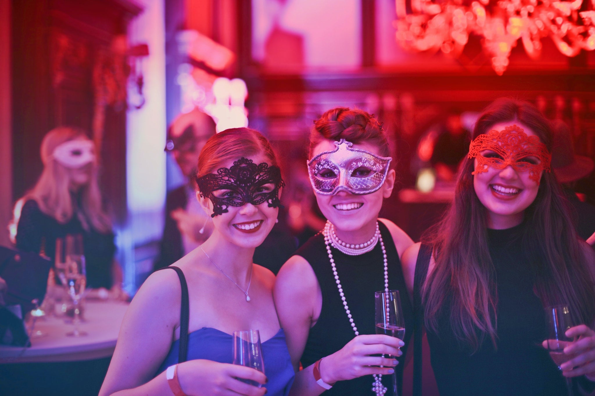 masked girls in a bar with drinks in hand